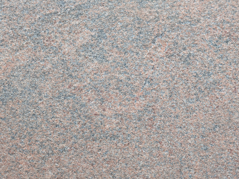 Nahaufnahme einer geflammt & gebürsteten Naturstein-Oberfläche mit rauer, rutschhemmender Textur.