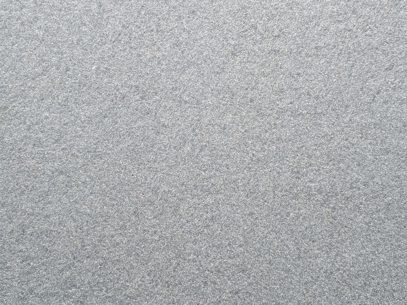 naturstein oberflaeche geflammt Nahaufnahme einer geflammten Naturstein-Oberfläche mit rauer, rutschhemmender Textur.